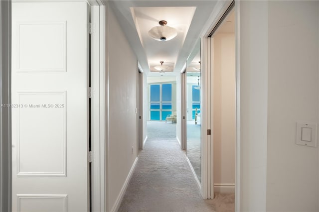 hall featuring baseboards, light carpet, and attic access