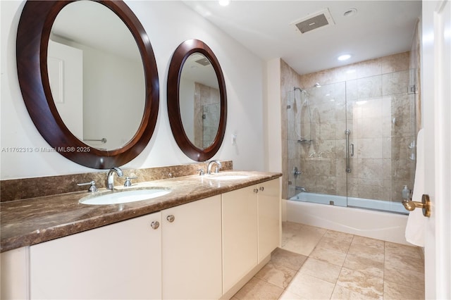 full bath with a sink, visible vents, bath / shower combo with glass door, and double vanity