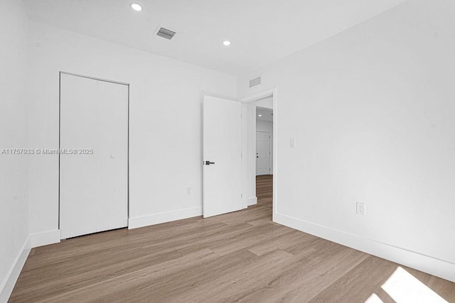 unfurnished bedroom with visible vents, recessed lighting, baseboards, and wood finished floors