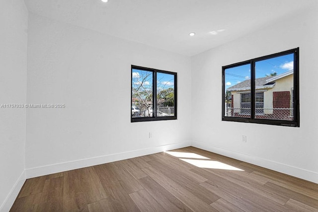 spare room featuring recessed lighting, baseboards, and wood finished floors