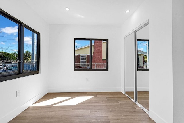 unfurnished bedroom with multiple windows, baseboards, and wood finished floors