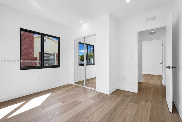 unfurnished bedroom with visible vents, wood finished floors, recessed lighting, a closet, and baseboards