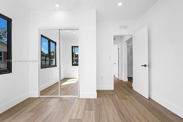 unfurnished bedroom with visible vents, baseboards, recessed lighting, wood finished floors, and a closet