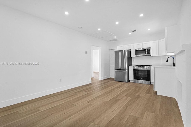 kitchen with light wood finished floors, visible vents, appliances with stainless steel finishes, white cabinetry, and a sink