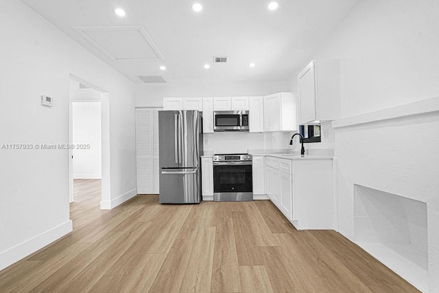 kitchen with visible vents, light wood-style flooring, appliances with stainless steel finishes, white cabinets, and a sink