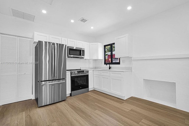 kitchen featuring white cabinetry, visible vents, light wood finished floors, and stainless steel appliances