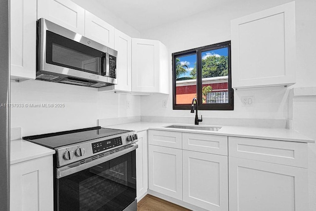 kitchen featuring a sink, appliances with stainless steel finishes, light countertops, and white cabinetry