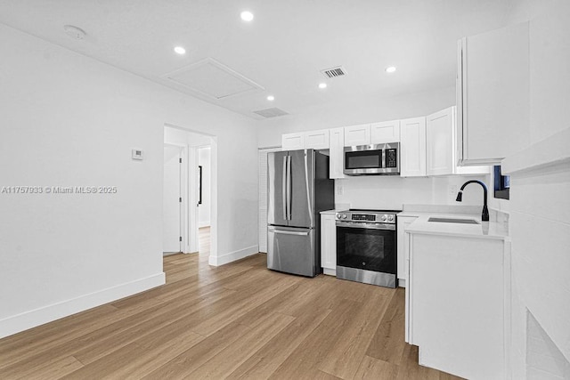 kitchen with visible vents, light wood-style flooring, a sink, appliances with stainless steel finishes, and light countertops