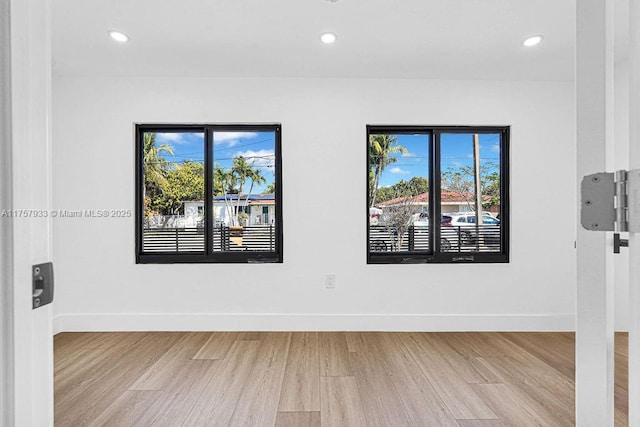 empty room with wood finished floors, recessed lighting, a healthy amount of sunlight, and baseboards