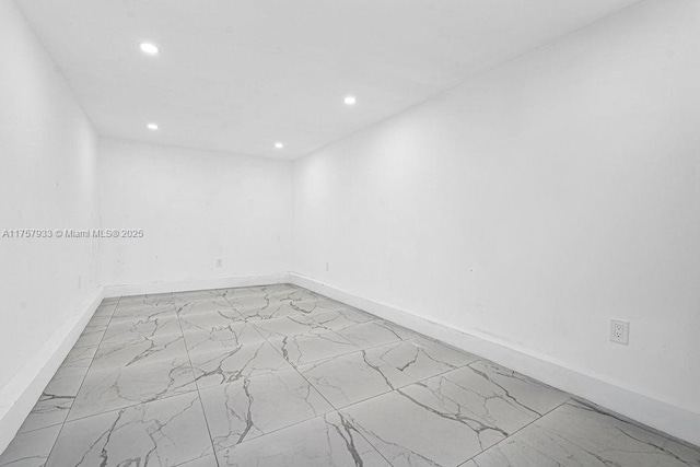 empty room with recessed lighting, baseboards, and marble finish floor