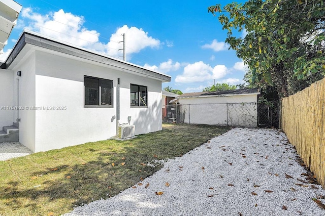 exterior space with a yard, central AC unit, stucco siding, and a fenced backyard