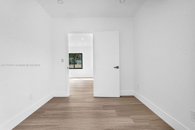 spare room featuring recessed lighting, baseboards, and wood finished floors