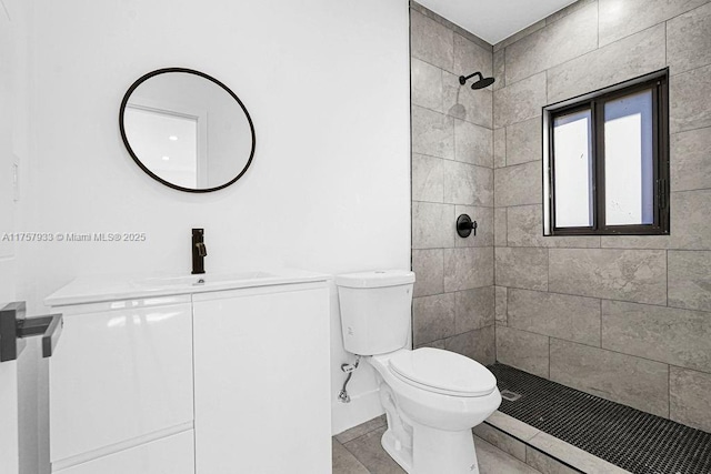 bathroom with toilet, vanity, and a tile shower