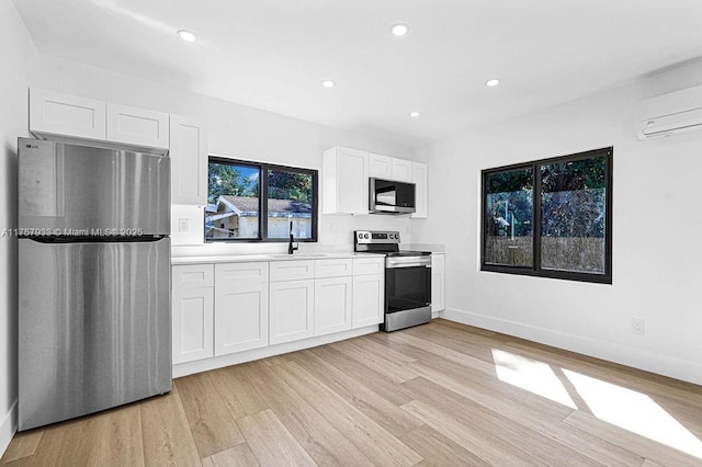 kitchen featuring stainless steel appliances, light wood-style flooring, and white cabinetry