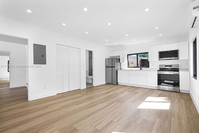 unfurnished living room with baseboards, electric panel, recessed lighting, a wall mounted air conditioner, and light wood-type flooring