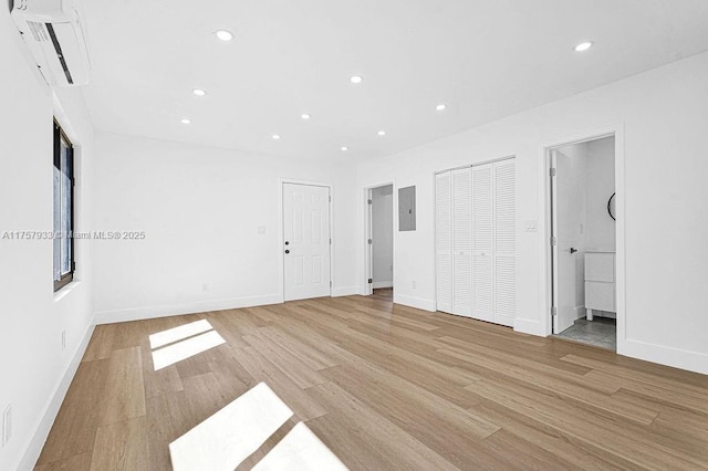 unfurnished bedroom with a wall mounted air conditioner, light wood-type flooring, and recessed lighting