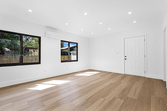 empty room with recessed lighting, light wood-style flooring, baseboards, and a wall unit AC