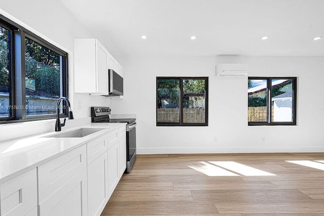 kitchen featuring electric range, a wall mounted air conditioner, light wood-style floors, and a sink