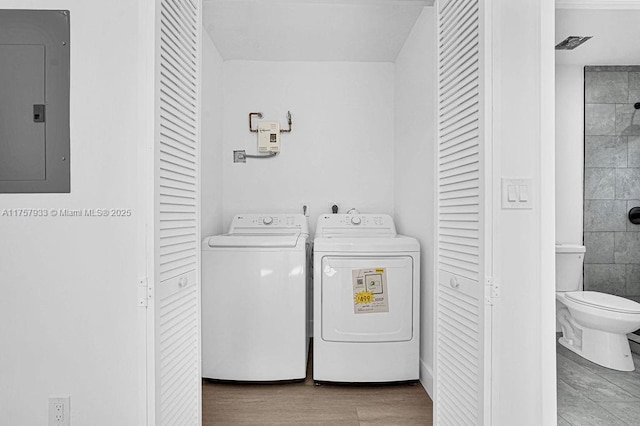 washroom with laundry area, electric panel, separate washer and dryer, and wood finished floors