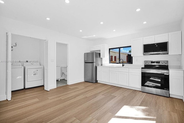 kitchen featuring light wood-style flooring, white cabinetry, appliances with stainless steel finishes, light countertops, and washing machine and clothes dryer