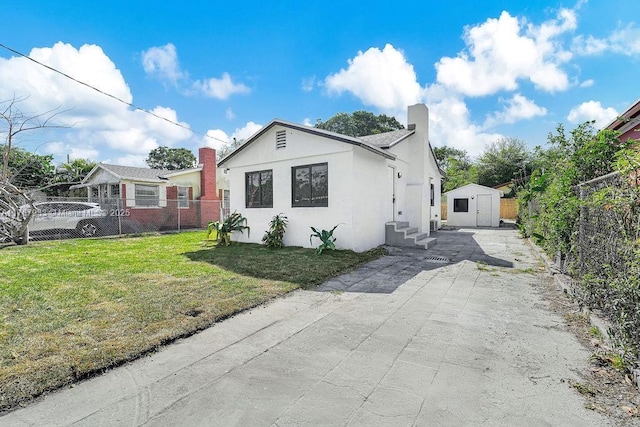 view of front facade with a front lawn, a storage unit, fence private yard, and an outbuilding