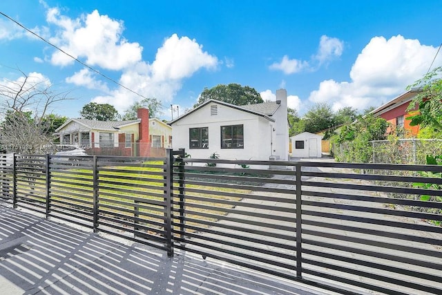 bungalow-style home featuring a fenced front yard, a front yard, a chimney, and a gate