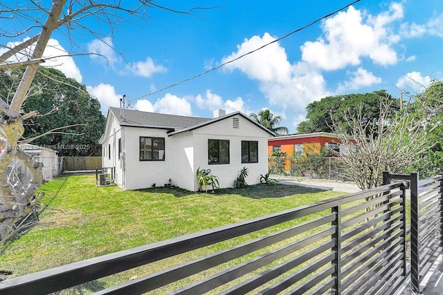 view of side of home with stucco siding, cooling unit, a yard, and a fenced backyard