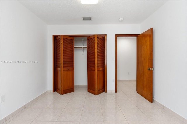 232 NW 58th Ct, Miami, FL 33126 - unfurnished bedroom with a closet, visible vents, a textured ceiling, and light tile patterned floors