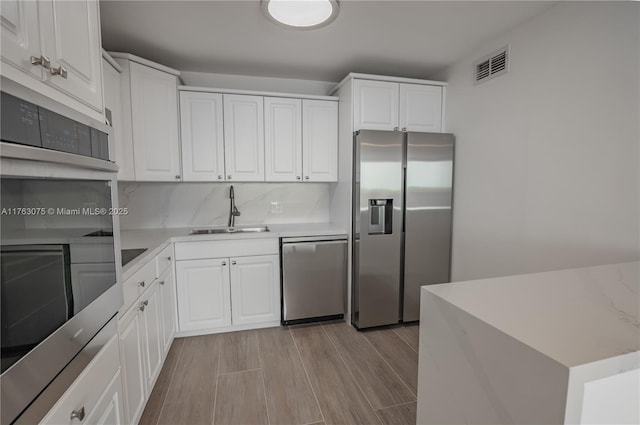 kitchen featuring visible vents, a sink, appliances with stainless steel finishes, white cabinets, and light countertops