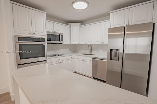 kitchen with white cabinetry, light countertops, appliances with stainless steel finishes, and a sink