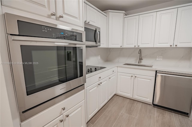 kitchen with light countertops, white cabinets, appliances with stainless steel finishes, and a sink