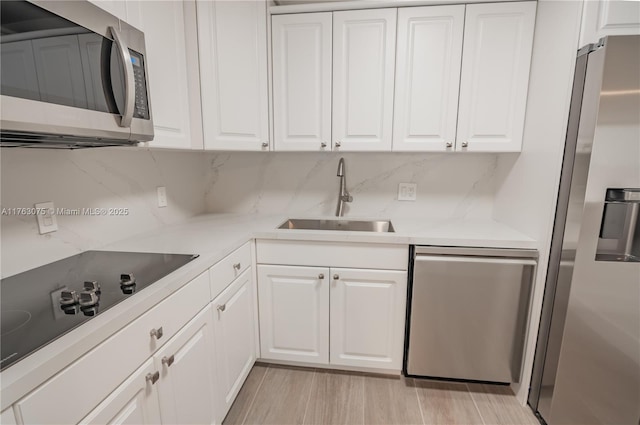 kitchen featuring a sink, appliances with stainless steel finishes, light countertops, and white cabinetry