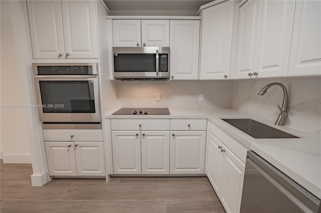 kitchen with a sink, tasteful backsplash, appliances with stainless steel finishes, and white cabinetry