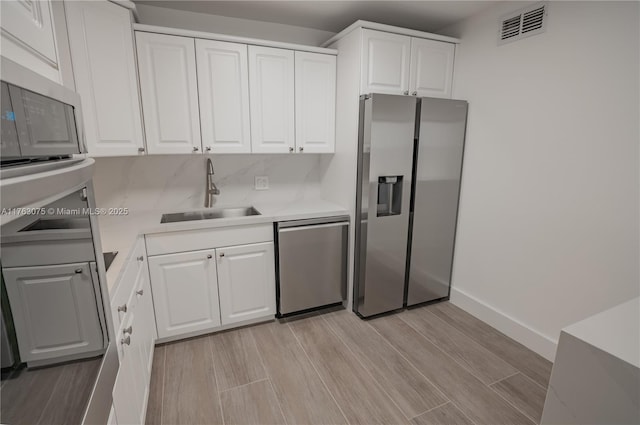 kitchen featuring a sink, white cabinets, visible vents, and stainless steel appliances