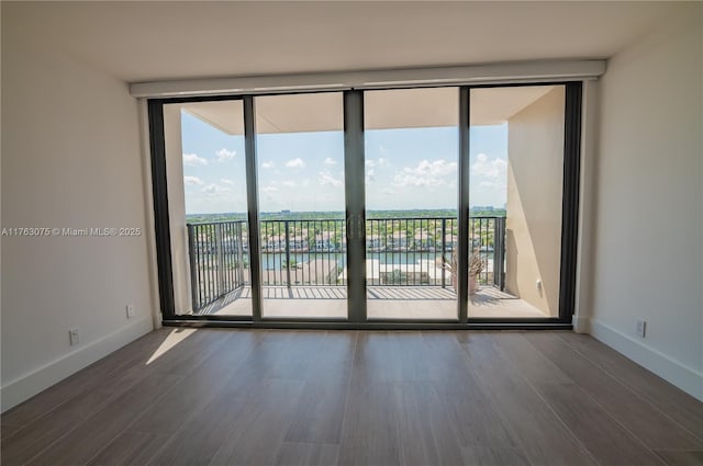 spare room with a wall of windows, baseboards, and wood finished floors