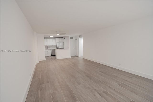 unfurnished living room with a sink, light wood-style floors, baseboards, and ceiling fan