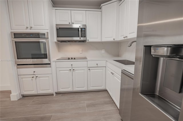 kitchen featuring wood tiled floor, light countertops, stainless steel appliances, white cabinetry, and a sink