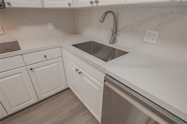 kitchen with dishwasher, decorative backsplash, light wood-style floors, white cabinets, and a sink