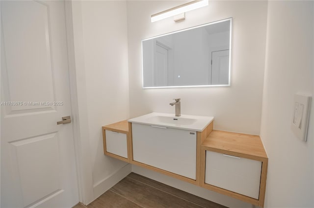 bathroom with baseboards, wood finished floors, and vanity