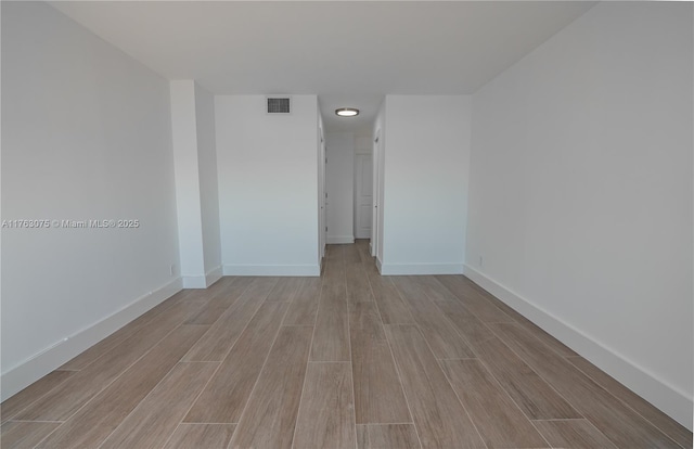 unfurnished room with visible vents, baseboards, and wood tiled floor