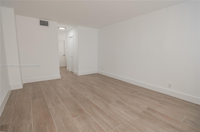 empty room featuring visible vents, baseboards, and wood tiled floor