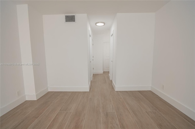 unfurnished room with visible vents, baseboards, and wood tiled floor