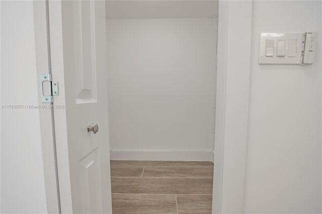 corridor featuring baseboards and wood finished floors