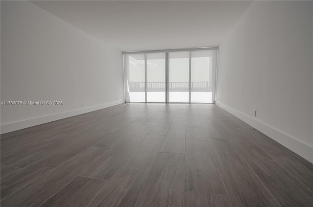 spare room featuring expansive windows, baseboards, and dark wood-style flooring