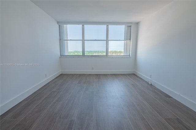 spare room with dark wood-type flooring and baseboards