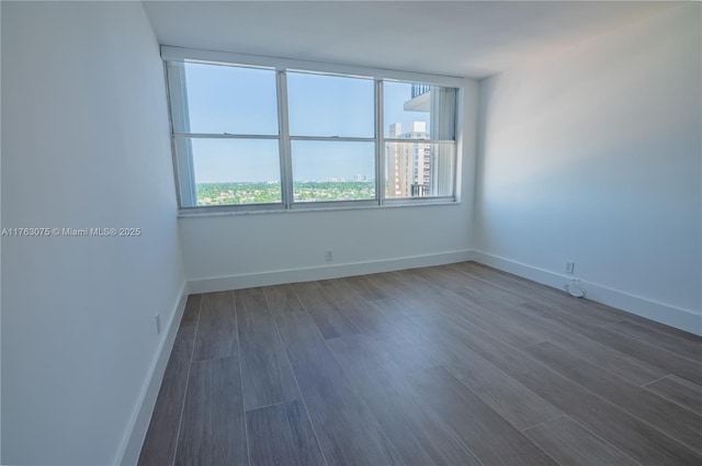 empty room featuring baseboards and dark wood-style floors