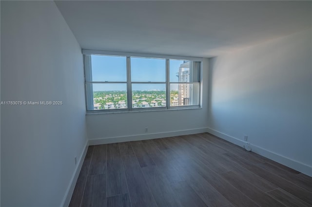 spare room featuring dark wood finished floors and baseboards