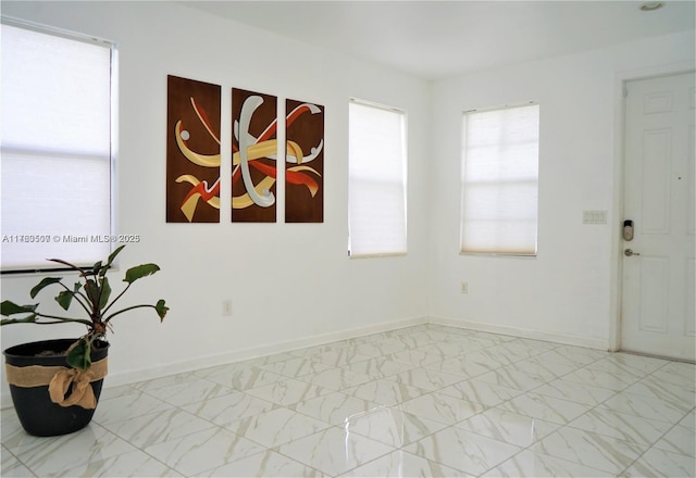 empty room featuring baseboards and marble finish floor