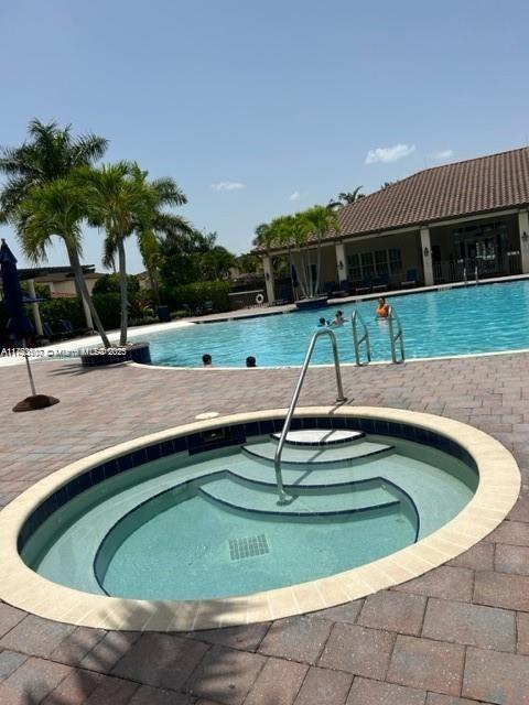 pool with a patio and a community hot tub