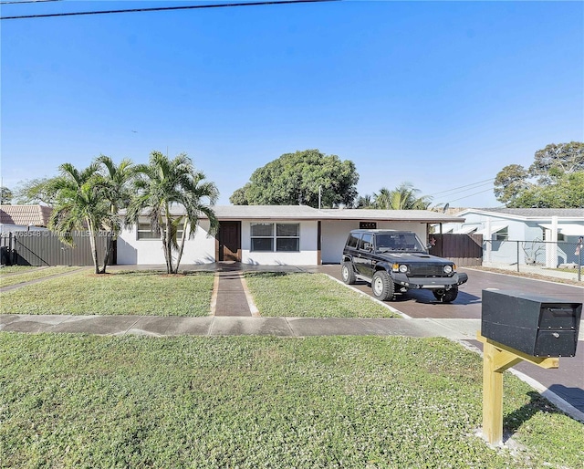 ranch-style house with a front lawn, fence, and driveway